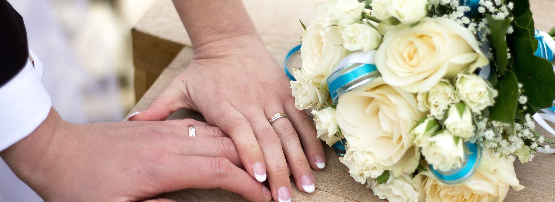 Woman's hand over man's hand next to wedding flowers